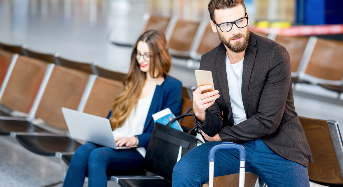 Casal sentado em cadeiras no aeroporto, aguardando o embarque para uma viagem internacional, simbolizando a importância de ter a documentação necessária em mãos.